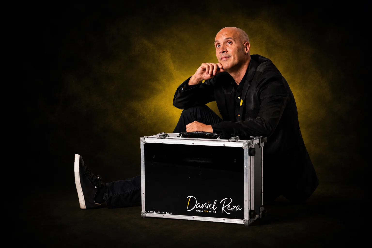 Daniel Reza, mago profesional en Barcelona, posando con su maleta de magia y efecto de luz amarilla.