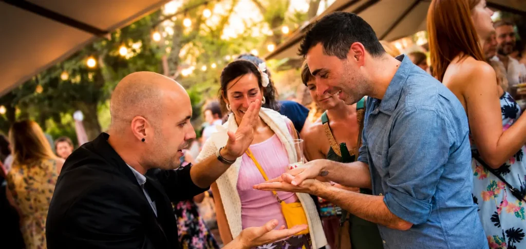 Daniel Reza realizando magia de cerca en un aniversario con invitados sorprendidos