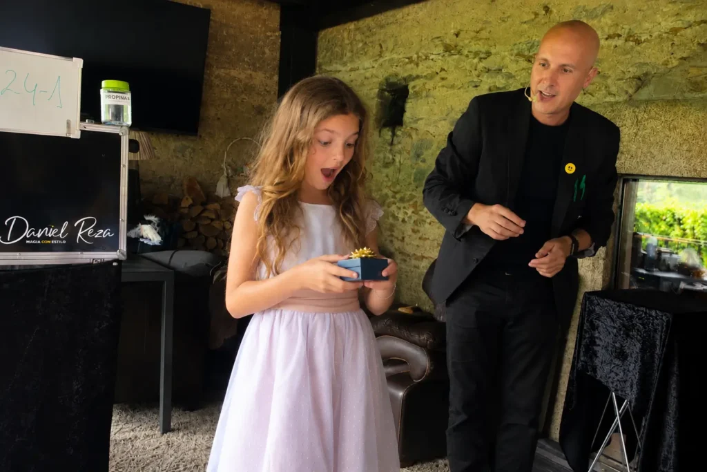 Niña sorprendida recibiendo un regalo mágico durante un espectáculo de magia para comuniones
